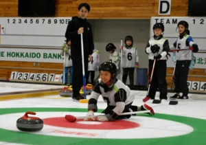 カーリングのストーンを投げる練習をする子どもたち