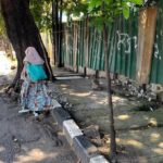 Pejalan kaki terpaksa melintasi bahu jalan akibat trotoar berlubang.