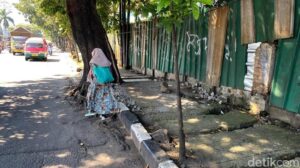 Pejalan kaki terpaksa melintasi bahu jalan akibat trotoar berlubang.
