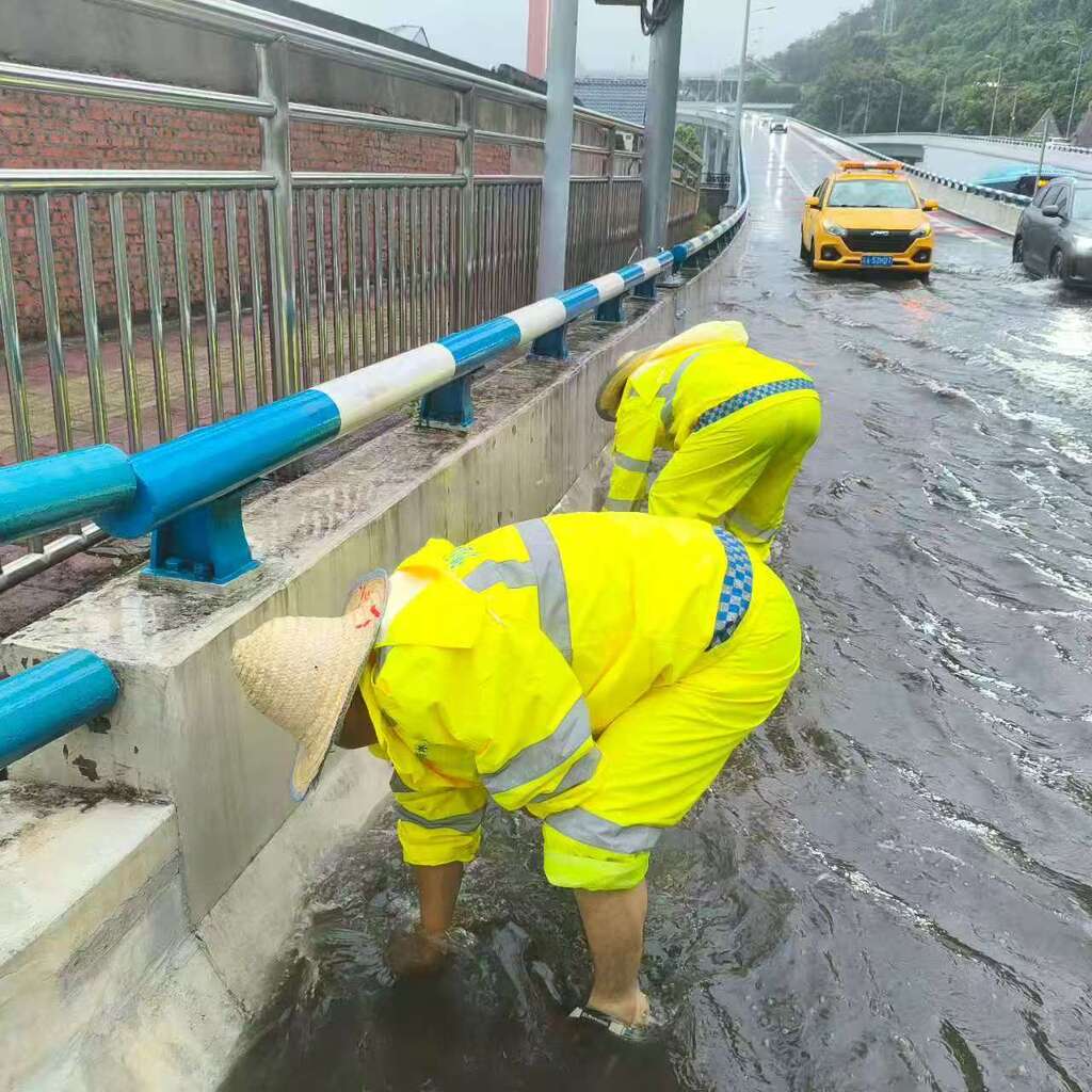 Workers clearing blocked drains under Hongyan Village Bridge in Shapingba District.