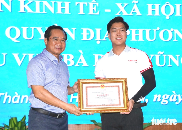 Chủ tịch UBND TP.HCM tặng bằng khen tuyên dương anh Cao Thành Đạt - Ảnh: ĐÔNG HÀ