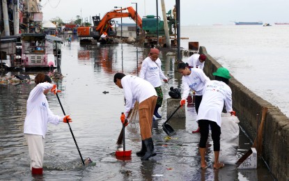COMMUNITY EFFORT. Residents of Baseco Compound, armed with protective gears such as boots and gloves, join a cleanup drive amid flooding in Tondo, Manila in this September 2024 file photo. The Department of the Interior and Local Government encourages communities to clean their surrounding as mandated by the KALINISAN (Kalinga at Inisyatiba para sa Malinis na Bayan) program. (PNA photo by Yancy Lim)