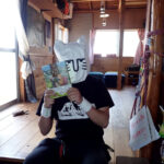 漫画「今日からはじめる山登り」を手にポーズを取るじゅごん大輔さん＝４月２７日、表丹沢の木ノ又小屋