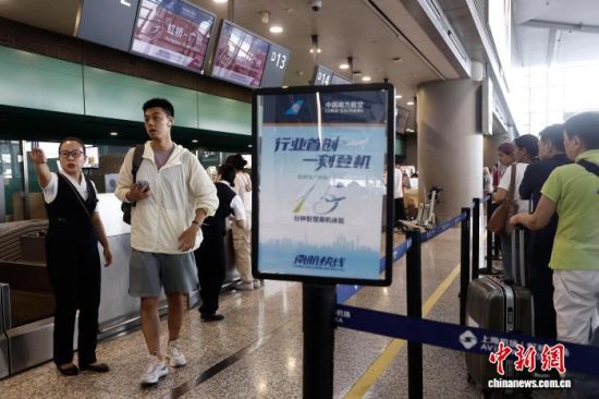 南航工作人员引导旅客前往安检通道。中新网记者 殷立勤 摄