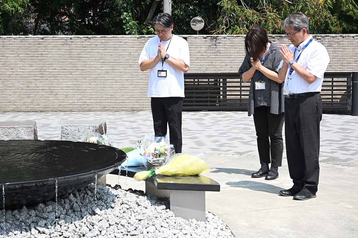 鎮魂のモニュメントに花を手向け、手を合わせる園職員ら＝２６日午前、津久井やまゆり園