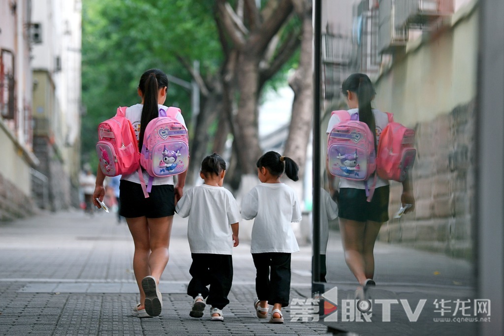A parent walks two children to school.