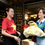 Chị Chung Tuyết Nhung (bên phải), quê Cao Bằng, vui cười nhận bánh mì, nước miễn phí tại số 3 Ngõ Thanh Miến, Văn Miếu - Quốc Tử Giám, Hà Nội - Ảnh: HÀ QUÂN