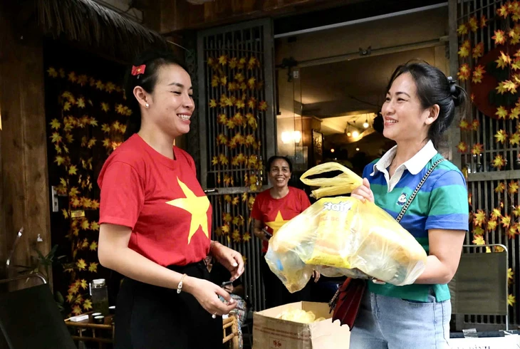 Chị Chung Tuyết Nhung (bên phải), quê Cao Bằng, vui cười nhận bánh mì, nước miễn phí tại số 3 Ngõ Thanh Miến, Văn Miếu - Quốc Tử Giám, Hà Nội - Ảnh: HÀ QUÂN