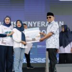 Bupati Simalungun, Anton Achmad Saragih (kanan) didampingi Weni Mega Sari, Pemimpin Cabang PNM Pematangsiantar (kiri), menyerahkan hadiah umroh kepada nasabah PNM.