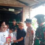 Camat Nurchinta Depi Tambunan menggendong bayi didampingi Wakapolsek Tanjung Beringin Iptu Zulfan Ahmad, personel Koramil 11/TB Sertu Budi Santoso dan Kepala Desa Mangga Dua, Budi Santoso di rumah warga yang terdampak banjir di Dusun IV Kebun Sayur, Desa Mangga Dua.
