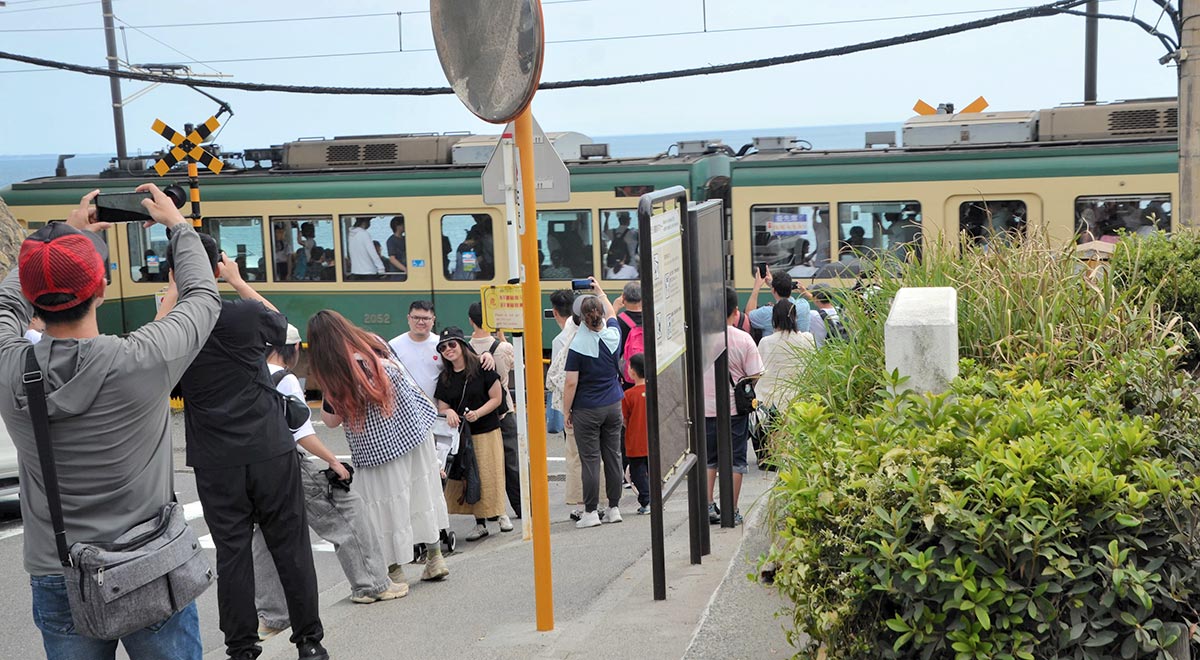 平日にも関わらず多くの観光客が詰めかける江ノ島電鉄鎌倉高校前駅＝８月、鎌倉市腰越