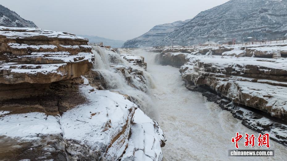 Snow falls on the Hukou Waterfall of the Yellow River, painting a beautiful scene of silver-clad cascades.
