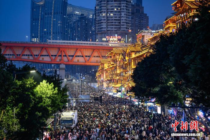 2月19日，农历大年初三，夜晚的洪崖洞灯火辉煌，游人如织。春节假期，位于重庆市渝中区的洪崖洞景区迎来客流高峰，为保障游客安全，提升观赏体验，当地启动临时交通管制，将洪崖洞前道路封闭，暂停社会车辆通行，方便游客赏景游玩。中新社记者 何蓬磊 摄