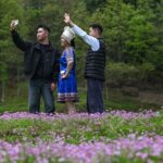 3月26日，在重庆市武隆区石桥苗族土家族乡八角村，游客与当地村民在紫云英花海中合影。新华社记者 陈诚 摄