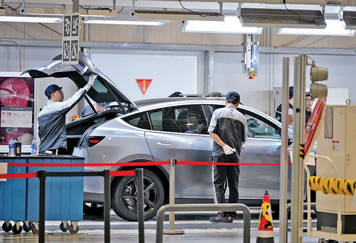 Workers check on Tesla model Y at the Tesla Gigafactory in Sanghai