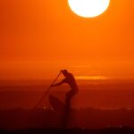 A man on a paddle board surfs during sunset at La Torche, as a heat wave hits France, in Plomeur, Brittany, France, September 6, 2021. REUTERS/Pascal Rossignol