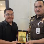 Kajari Medan, Ridwan Sujana Angsar saat menyerahkan cinderamata berupa plakat kepada Forwakum Sumut diwakilkan Sekretaris Ansah Tarigan dalam pertemuan sederhana di Medan.