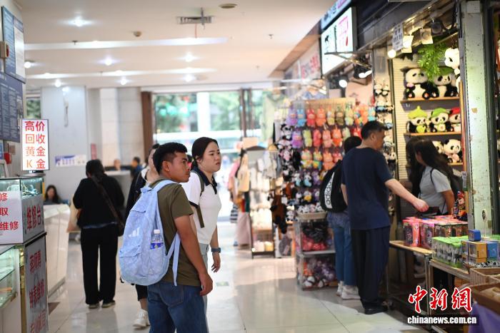 4月11日，两位泰国游客(左一、左二，背着包的男女)正在逛位于重庆市渝中区的新重庆国际小商品批发中心。张旭 摄