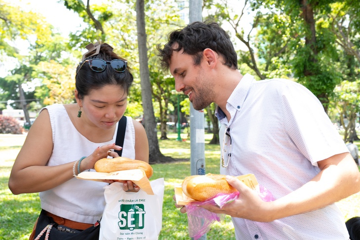 Du khách nước ngoài trải nghiệm ẩm thực với bánh mì - Ảnh: HỮU HẠNH