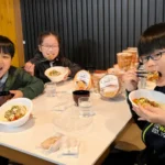 こみかの子ども食堂を訪れ、笑顔で食事をほおばる小学生