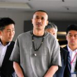 マレーシアで拘束され、成田空港に移送された高橋伸明容疑者（中央）。8年前に知人女性を殺害した容疑で逮捕された=2026年4月25日午前6時56分、成田空港、平川仁撮影