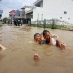 Anak anak bermain di air banjir yang menggenang Kawasan Baleendah. (eko sutrisno/radar badnung)
