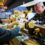 教え子たちと笑顔で乾杯する店主の佐藤裕寛さん（右）=12日、札幌市中央区（野沢俊介撮影）