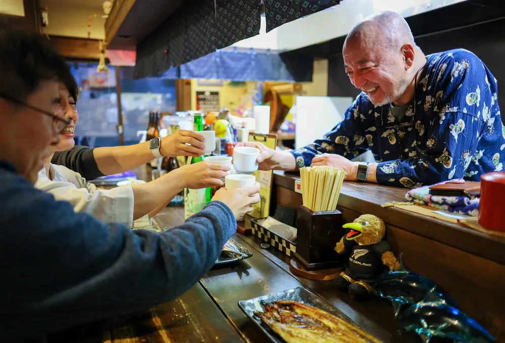 教え子たちと笑顔で乾杯する店主の佐藤裕寛さん（右）=12日、札幌市中央区（野沢俊介撮影）