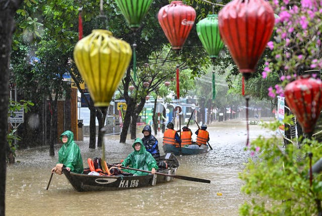 People navigate a flooded street on boats during heavy rains in Hoi An on 30 October 2025