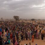ADRE, CHAD - APRIL 22: Refugees, mostly women and children wait for a WFP food distribution point to open at a temporary camp on April 22, 2024 in Adre, Chad. Since the beginning of the recent conflict between the paramilitary Rapid Support Forces (RSF) and the the Sudanese Armed Forces, (SAF), which began in March 2023, over 600,000 new refugees have crossed the border from Darfur in Sudan, into Chad. The total number of refugees, including those from previous conflicts, now stands at 1.2 million. Aid agencies, including The World Food Programme, (WFP), Médecins Sans Frontières (MSF) and the United Nations High Commissioner for Refugees, (UNHCR), already struggling with accute supply shortages, have warned that the life-saving programmes in Chad, will ‘grind to a halt in a matter of weeks without urgent funding’. Chad is now home to one of the largest and fastest-growing refugee populations in Africa. (Photo by Dan Kitwood/Getty Images)