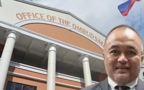 Front view of the Office of the Ombudsman building with orange facade and columns; a man in a suit stands in the foreground.