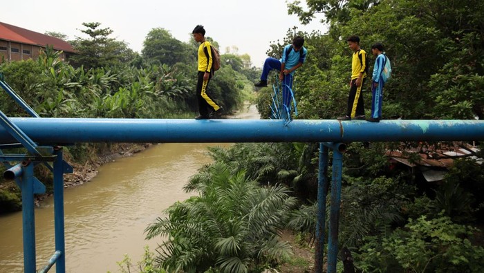 Sejumlah siswa berjalan melintasi pipa air di Kelurahan Kampung Baru, Medan, Sumatera Utara, Sabtu (18/4/2026). Sebagian siswa di daerah itu terpaksa berangkat dan pulang sekolah dengan melintasi pipa air karena jembatan yang biasa mereka lalui ambruk dan tak kunjung dibangun kembali. ANTARA FOTO/Yudi Manar/YU