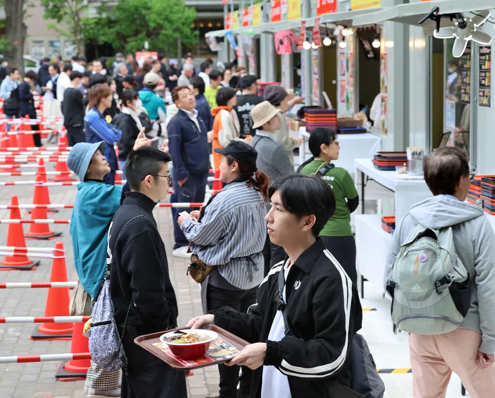 出店ブースでラーメンを受け取る来場者たち=18日（西野正史撮影）