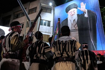 Bakhtiari nomads, wearing traditional dress, hold their guns during a pro-government gathering near the residence where former Iranian Supreme Leader Ayatollah Ali Khamenei, shown on a banner, was killed in U.S. and Israeli strikes on Feb. 28, in Tehran, Iran, May 18, 2026. (AP Photo/Vahid Salemi)