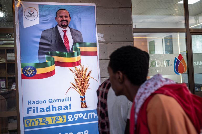 People walk past an election campaign poster depicting Ethiopia’s Prime Minister Abiy Ahmed in Jimma on May 27, 2026 ahead of Ethiopia’s general elections scheduled for June 1, 2026.