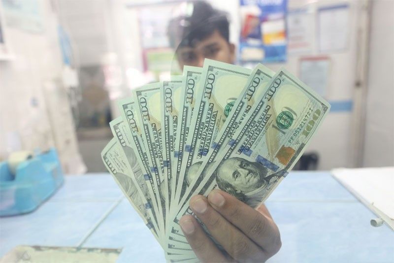 A money changer employee shows US dollar bills at their shop in Quezon City.