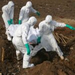 العاملون الصحيون يحملون جثة شخص يُشتبه بإصابته بفيروس إيبولا لدفنها في مقبرة بمدينة فريتاون، سيراليون (رويترز)
