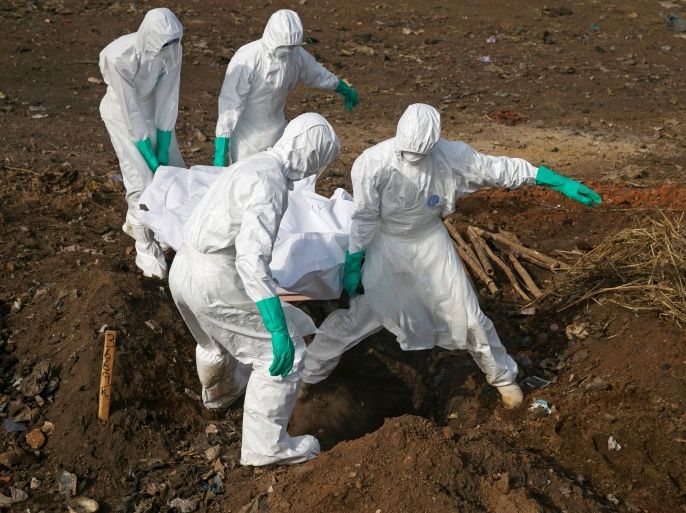 العاملون الصحيون يحملون جثة شخص يُشتبه بإصابته بفيروس إيبولا لدفنها في مقبرة بمدينة فريتاون، سيراليون (رويترز)