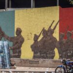 A motorcyclist rides past a monument in support of the Malian Army in Bamako on April 26, 2026. April 25, 2026's shock attacks, synchronised by Tuareg rebels of the Azawad Liberation Front (FLA) coalition and the jihadist Group for the Support of Islam and Muslims (JNIM), targeted several areas in the vast arid country. Fighting resumed on April 26 in several areas, including Kita near Bamako, Kidal, Gao and Severe. Tuareg rebels meanwhile announced an agreement allowing Russian forces backing Mali's army to withdraw from the northern city of Kidal, which they claimed was "totally" under their control. (Photo by AFP)