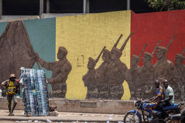 A motorcyclist rides past a monument in support of the Malian Army in Bamako on April 26, 2026. April 25, 2026's shock attacks, synchronised by Tuareg rebels of the Azawad Liberation Front (FLA) coalition and the jihadist Group for the Support of Islam and Muslims (JNIM), targeted several areas in the vast arid country. Fighting resumed on April 26 in several areas, including Kita near Bamako, Kidal, Gao and Severe. Tuareg rebels meanwhile announced an agreement allowing Russian forces backing Mali's army to withdraw from the northern city of Kidal, which they claimed was "totally" under their control. (Photo by AFP)