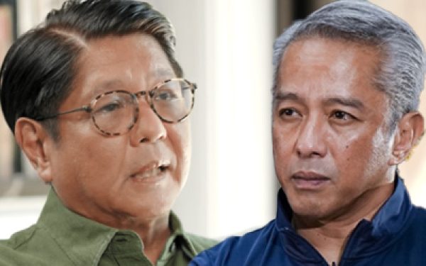 Two men engaged in a serious conversation, one wearing a green shirt and glasses, the other in a blue shirt with gray hair.