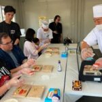Brittany Nevins and her husband Kevin, both from Erlander, Ky., try making sushi for the first time with a sushi master in Tokyo, on May 15, 2026. (AP Photo/Yuri Kageyama)