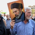 Người dân Iran xuống đường mang theo ảnh chân dung Lãnh tụ tối cao Iran Mojtaba Khamenei - Ảnh: AFP