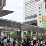 中野駅北口で中野区長選の候補者の演説を聞く人々。事業費高騰で再開発計画が白紙になった「中野サンプラザ」がみえる=2026年5月31日午後1時15分、東京都中野区、木佐貫将司撮影