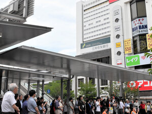 中野駅北口で中野区長選の候補者の演説を聞く人々。事業費高騰で再開発計画が白紙になった「中野サンプラザ」がみえる=2026年5月31日午後1時15分、東京都中野区、木佐貫将司撮影