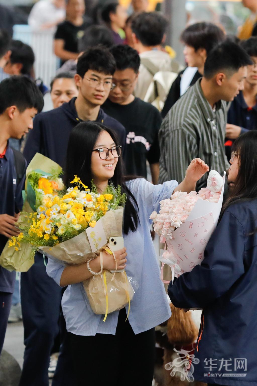 At Chongqing No.1 High School exam venue, after the second exam of the day, a candidate holds flowers from family and takes a photo at the school gate.