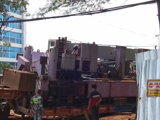 Container truck carrying ground nail machine sinks at Balai Patriot project, partially closing the road.