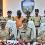 Arrested suspect in police custody with officers during a press conference at Siasat Daily.