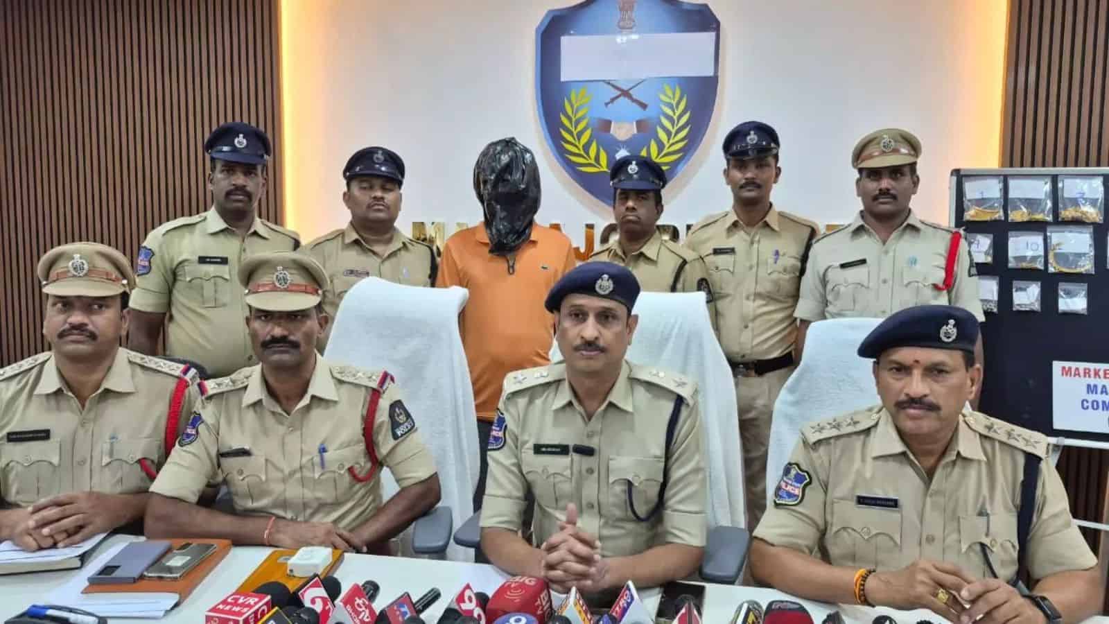 Arrested suspect in police custody with officers during a press conference at Siasat Daily.